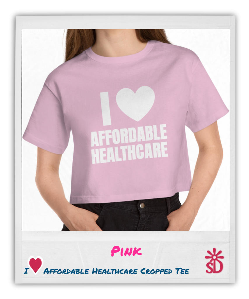 Person wearing a pink cropped t-shirt with white text and a heart graphic that reads "I [heart] Affordable Healthcare," shown from shoulders to waist against a white background.​
