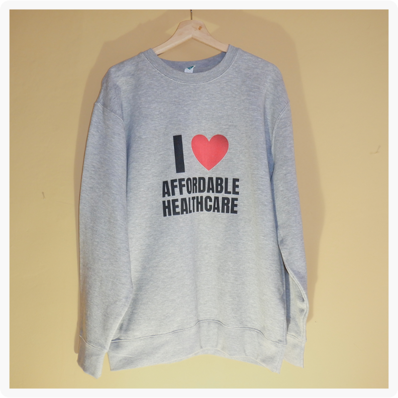 I Love Affordable Healthcare grey sweatshirt hanging on a wooden hanger